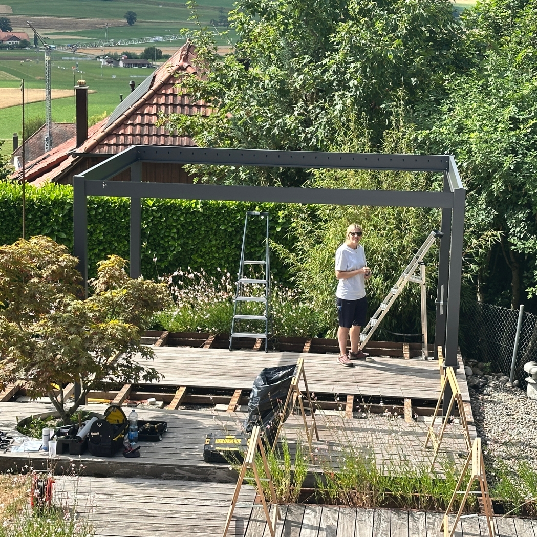 Montage einer Ventaris Pergola 3 mal 4 Meter im Garten, Rahmen steht, Monteur arbeitet am Aufbau